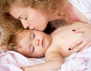 мама целует спящего ребенка
