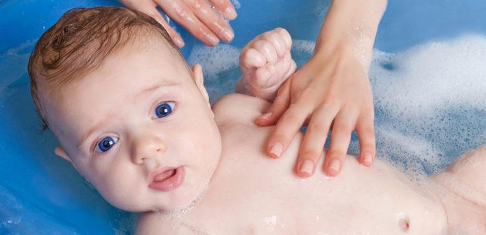 новорожденный купается в ванночке