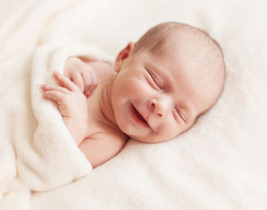 Новорожденный спит и улыбается