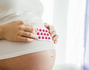 беременная держит таблетки на животе