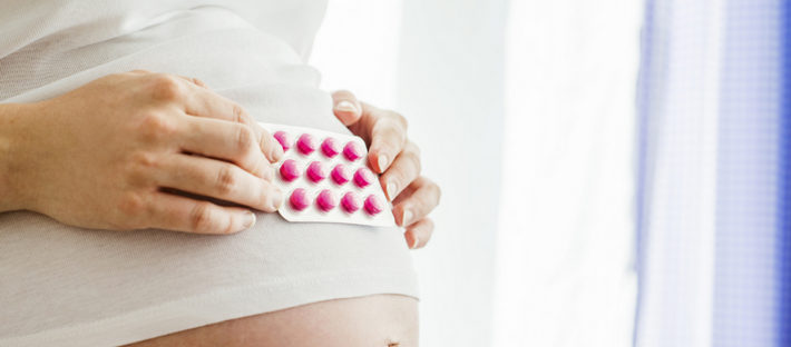 беременная держит таблетки на животе