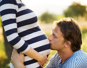 муж целует беременную жену