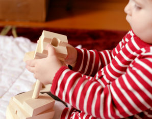 ребенок играет с деревянной игрушкой