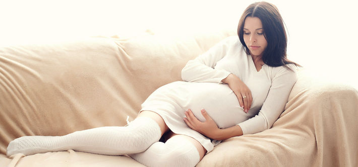 Красивая беременная сидит на диване