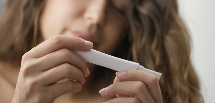 Женщина держит тест на беременность