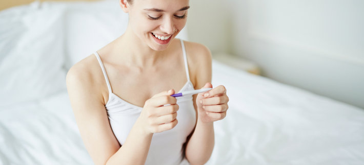 Женщина радуется тесту на беременность