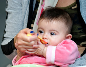 Маленького ребенка кормят с ложки