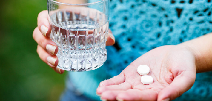 Женщина держит круглые белые таблетки