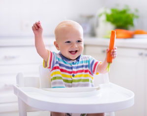 ребенок с морковокой за столом