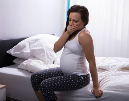 беременная закрыла рот рукой сидя на кровати