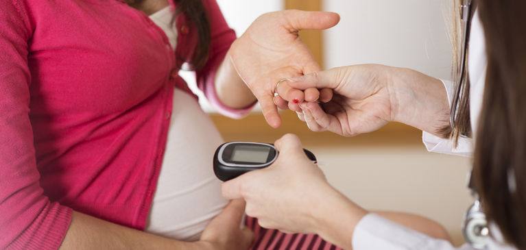 врач измеряет уровень сахара беременной глюкометром