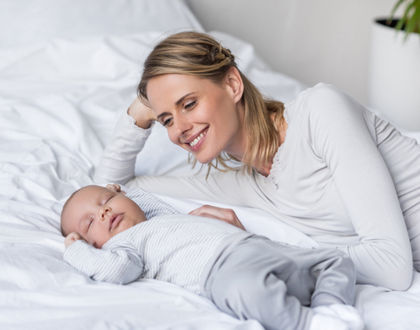 мама смотрит на спящего ребенка и улыбается