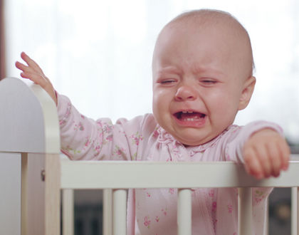 ребенок плачет стоя в кроватке