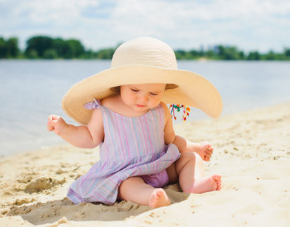 ребенок сидит на песке в шляпе