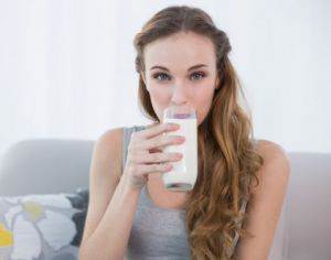 женщина со стаканом молока сидит на диване