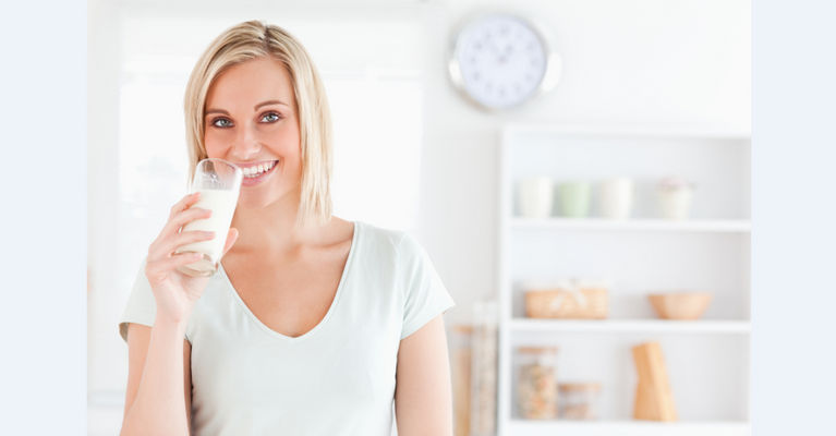 женщина пьет молочный напиток и улыбается
