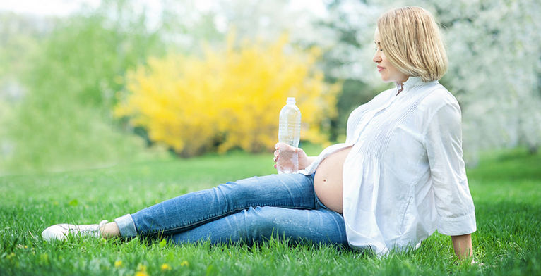 беременная пьет воду из бутылки